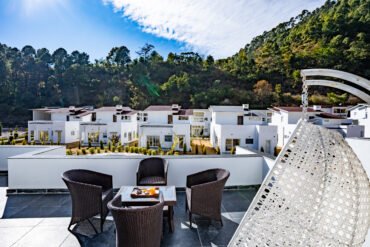 Terrace seating overlooking chalets and wooded hills at 3R Stays